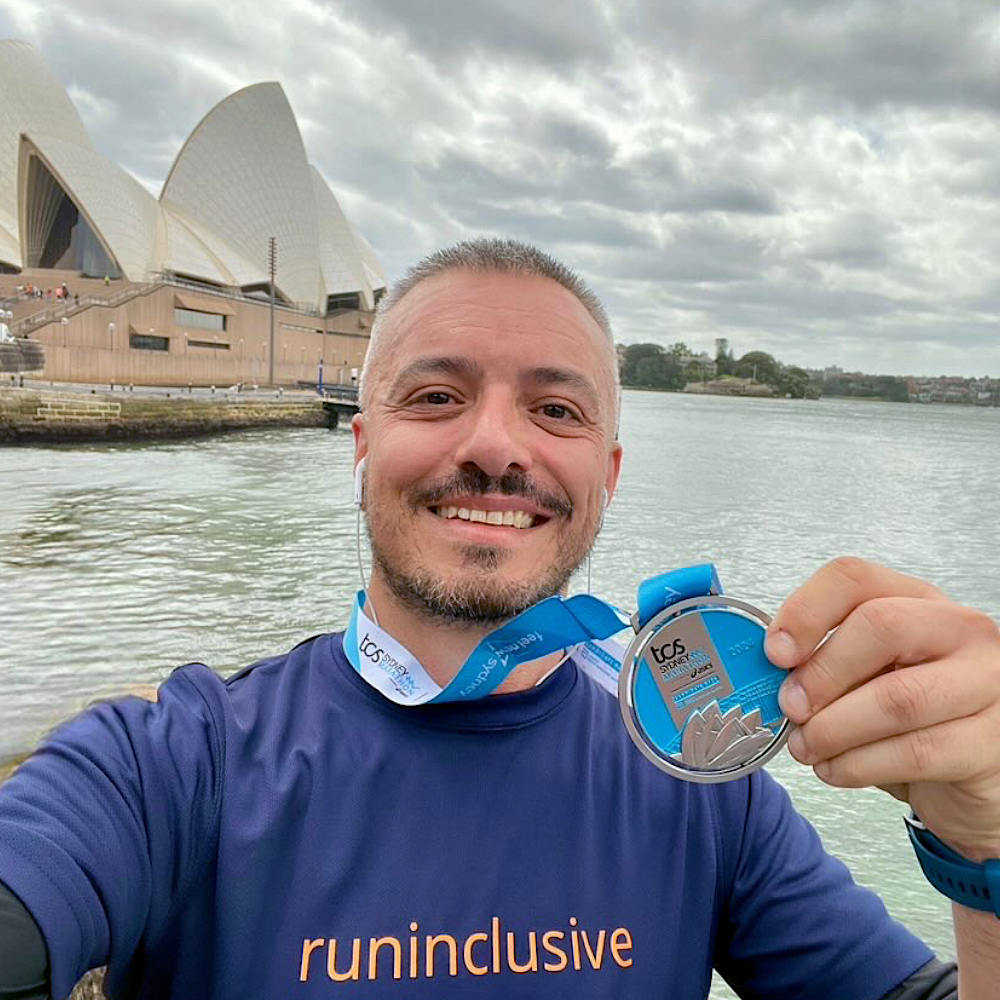 Dusan with his medal, wearing our Oxford Blue runinclusive t-shirt for the Sydney Marathon 2024